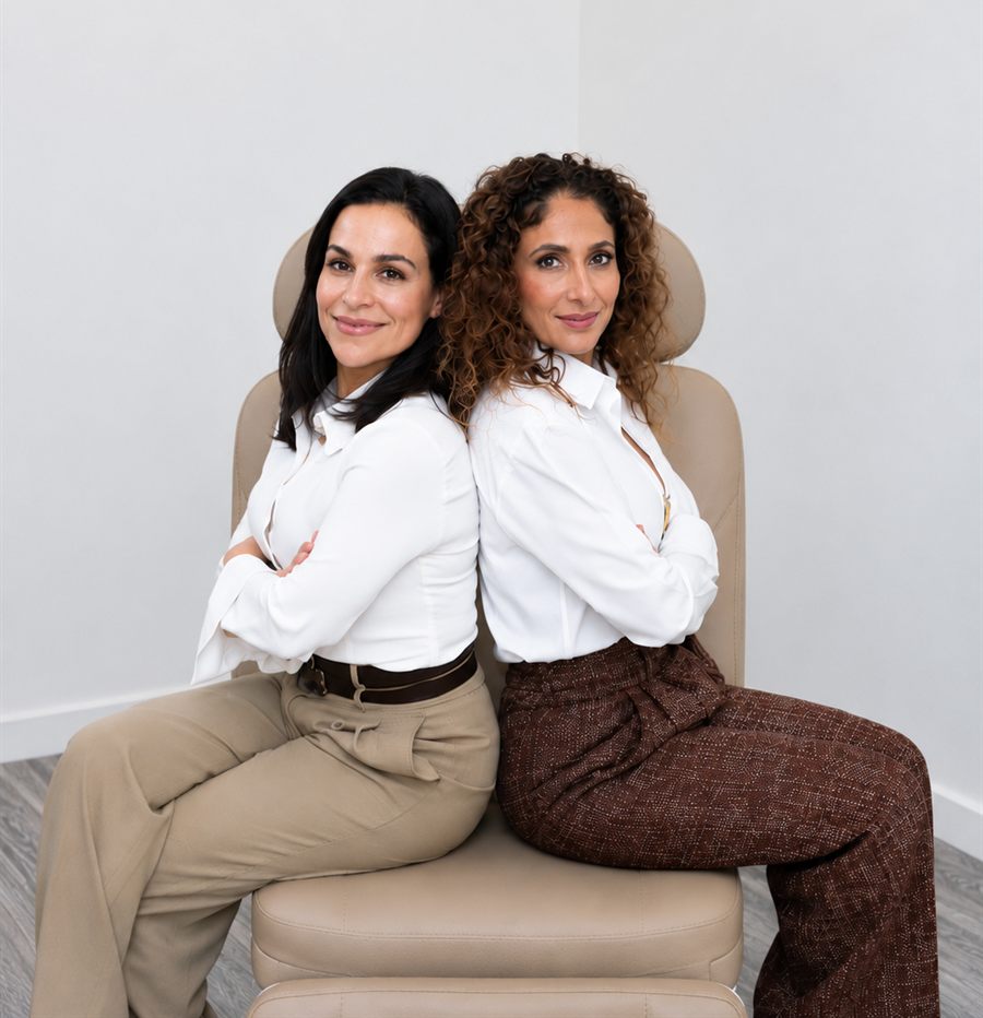 Dr. Sheila Omrani and Nurse Lisa Farazmand seated back to back in a treatment chair at their Great Neck practice.
