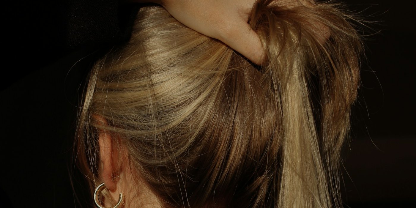 Hair lifted from the nape in warm light, showing the scalp and hair length.